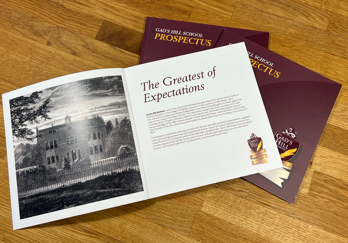 Open Gad’s Hill School prospectus showing a historic building illustration, with closed copies behind