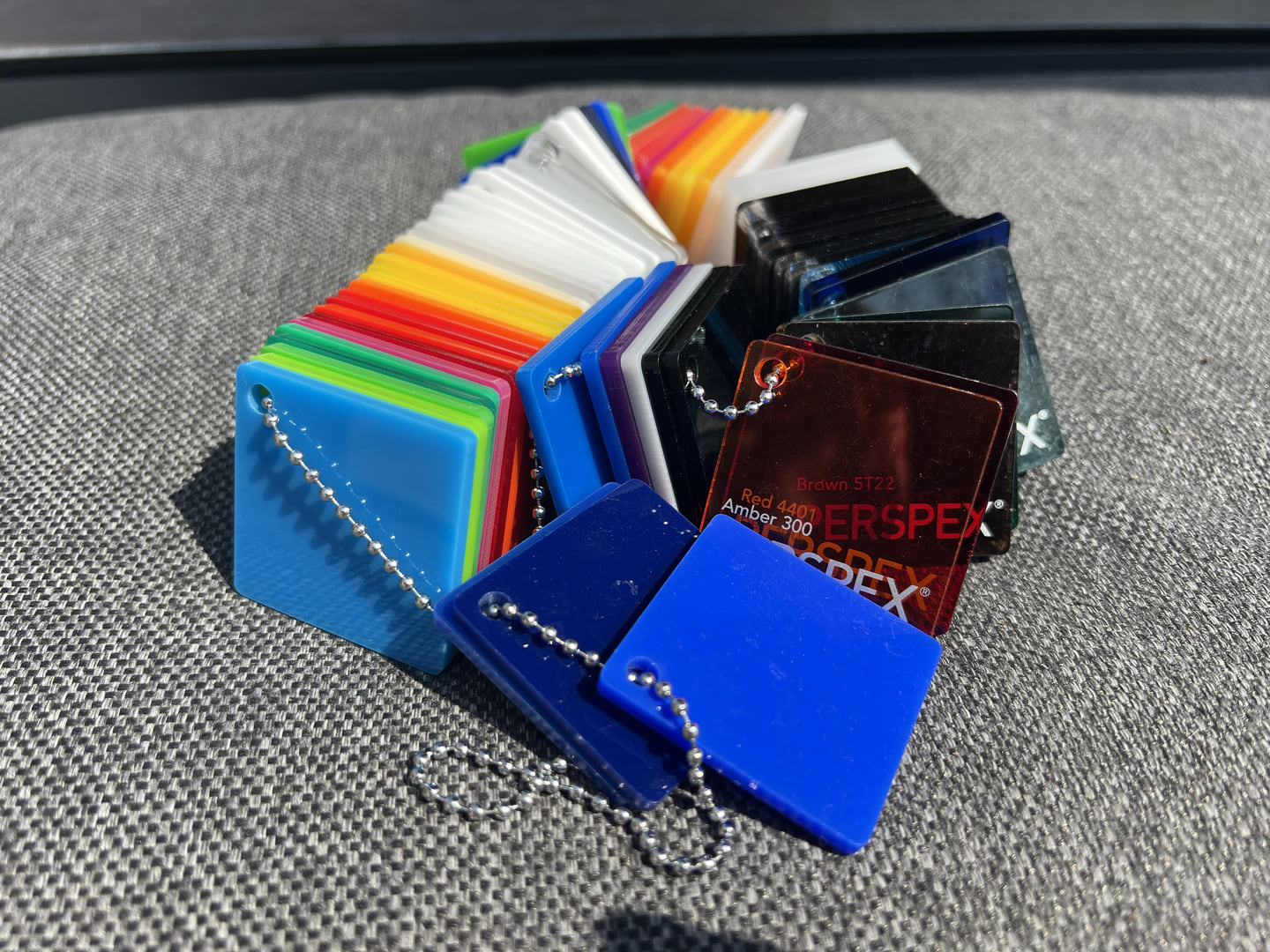 Fan of coloured Perspex acrylic swatches on a grey surface