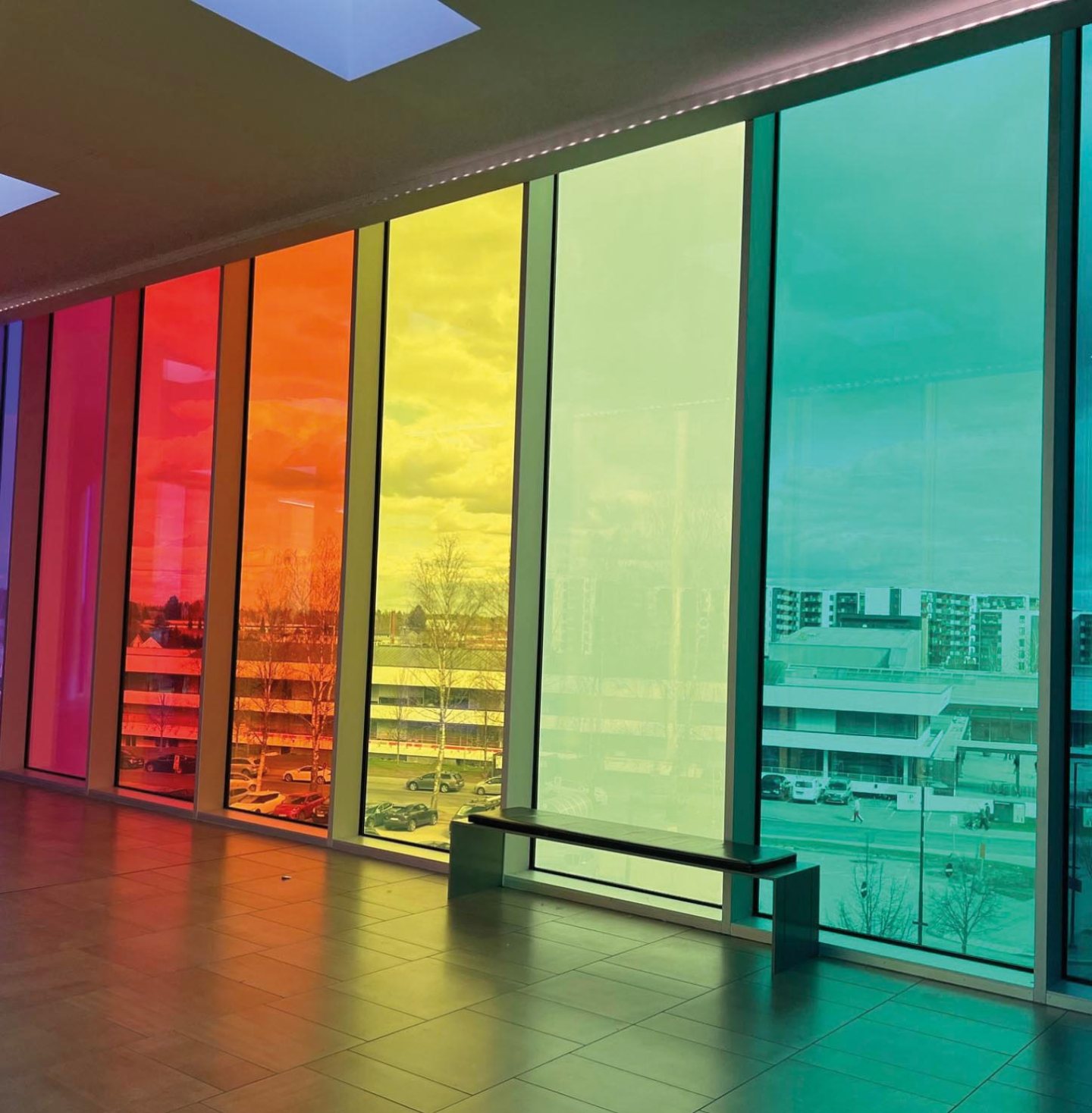 Colourful window graphics and frosted window film applied to floor-to-ceiling glass, creating vibrant red, orange, yellow, green and turquoise panels.