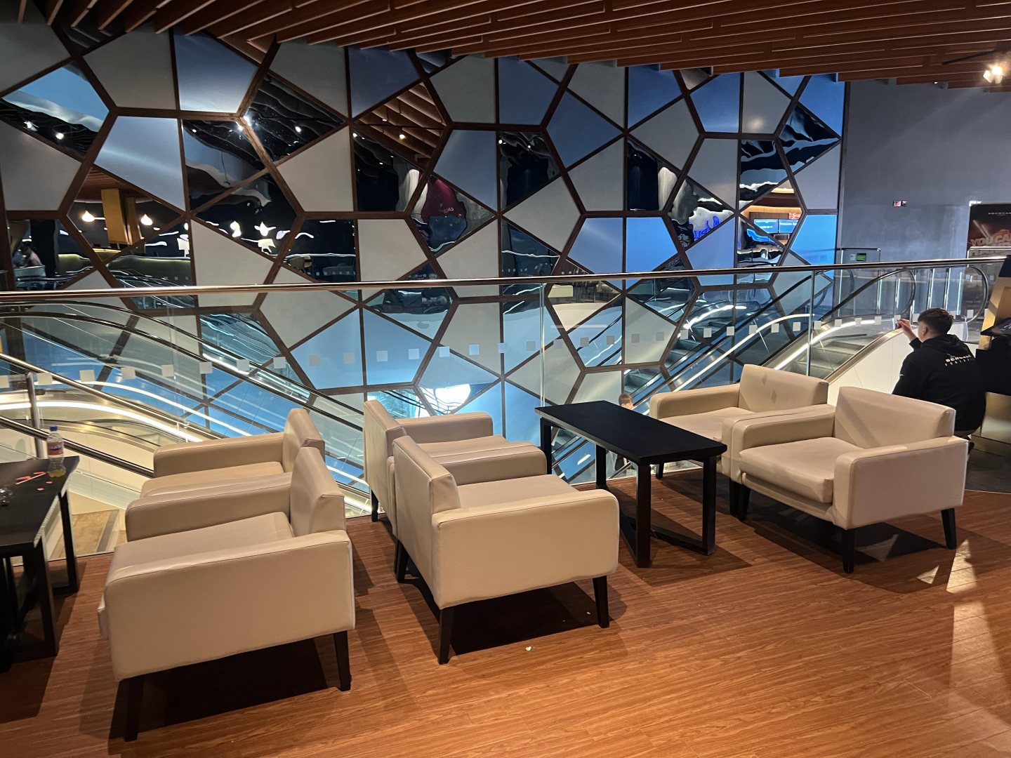 Glass balustrade with square manifestation safety stickers applied at regular intervals to improve visibility around an escalator area.