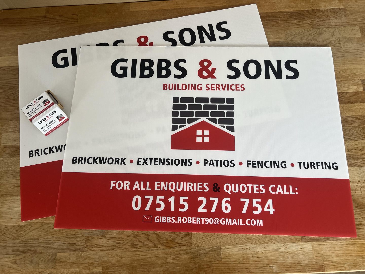 Printed Correx signs for Gibbs & Sons Building Services in red, black and white, displayed with matching business cards.