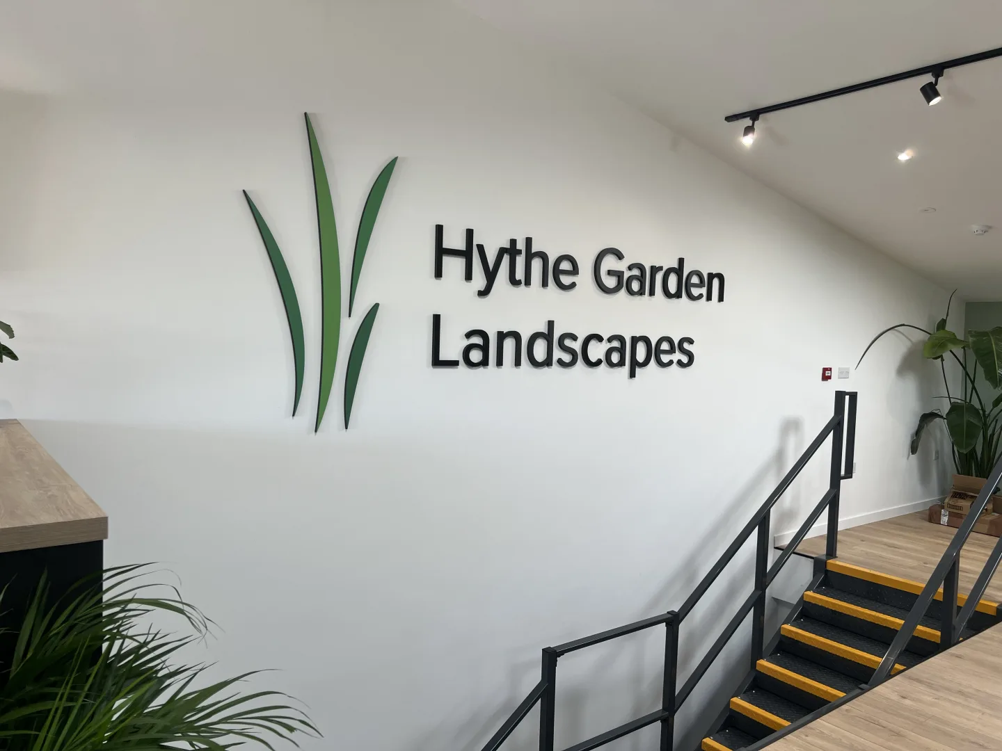 Black dimensional letters and a green graphic mounted on a white interior wall for Hythe Garden Landscapes