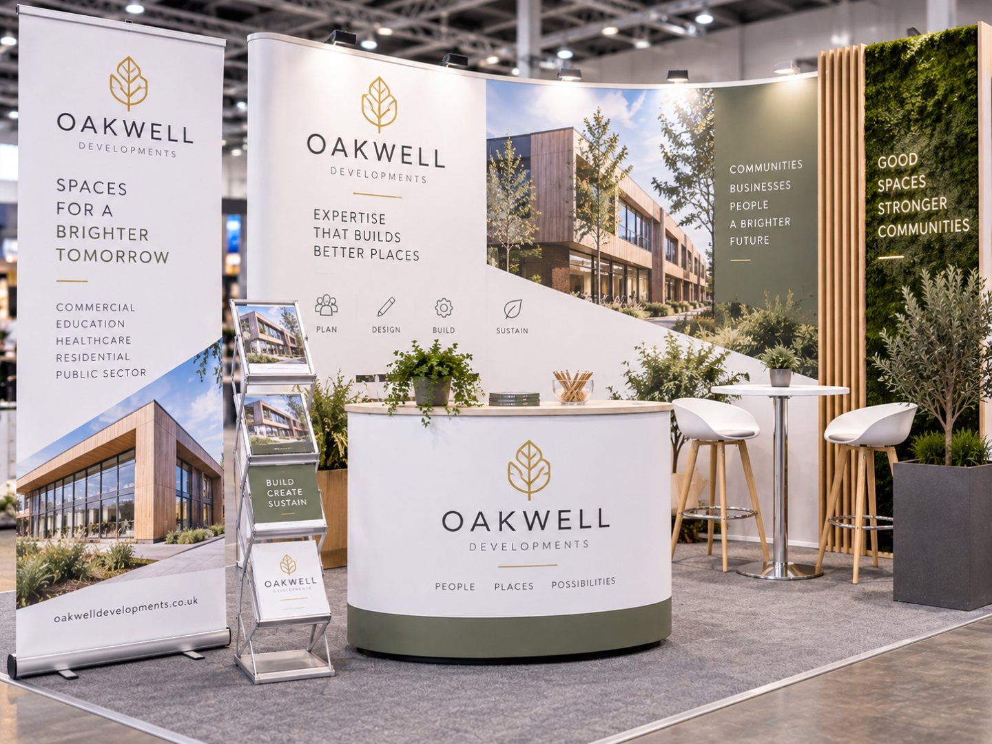 Illustration of an “Oakwell Developments” exhibition stand with a roller banner, curved display backdrop, branded counter and brochure rack in white, olive green and gold.
