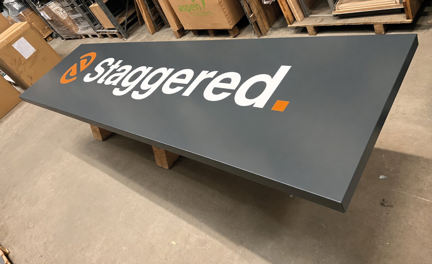 A powder-coated folded tray sign for Staggered, produced with crisp white and orange branding, shown during manufacture.