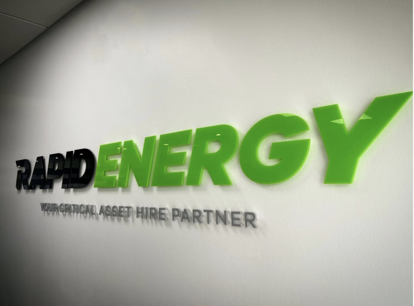 Rapid Energy acrylic wall lettering in black and bright green, mounted on stand-off fixings with grey tagline lettering below.